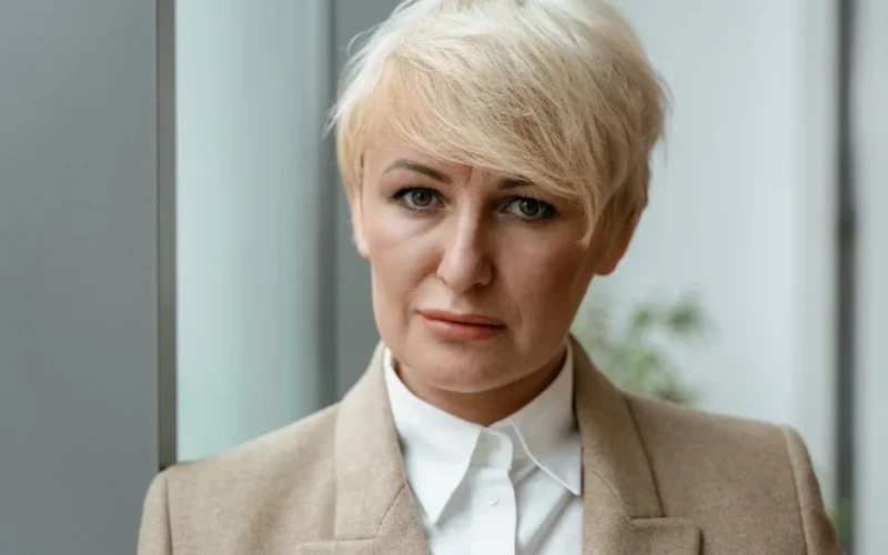 Confident woman with short blond hair in business attire indoors.