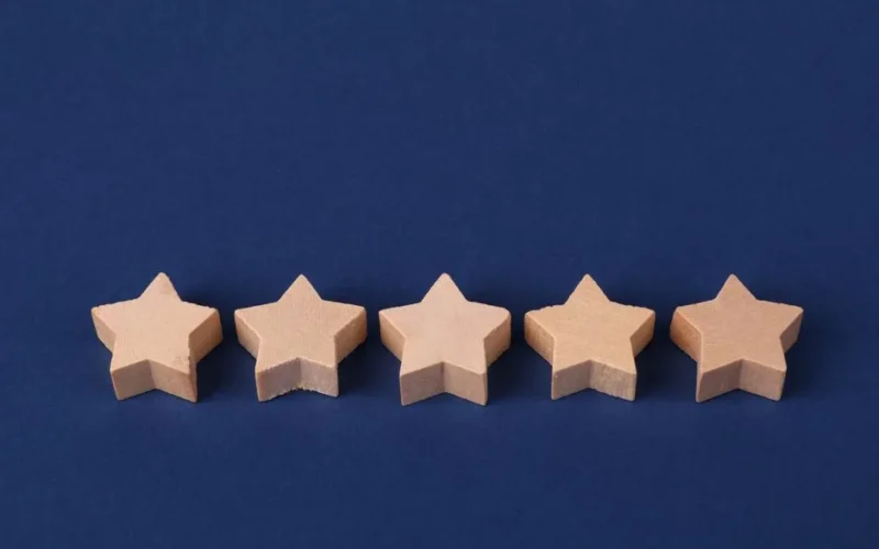 Five wooden stars on a blue background representing a rating system or evaluation concept.