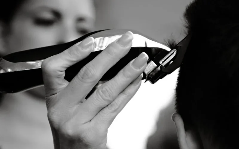 A close-up shot of a person receiving a haircut with electric clippers.