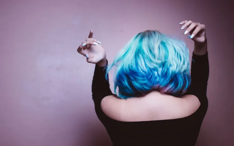 Back view of a woman with colorful blue and purple hair, stylish and expressive.