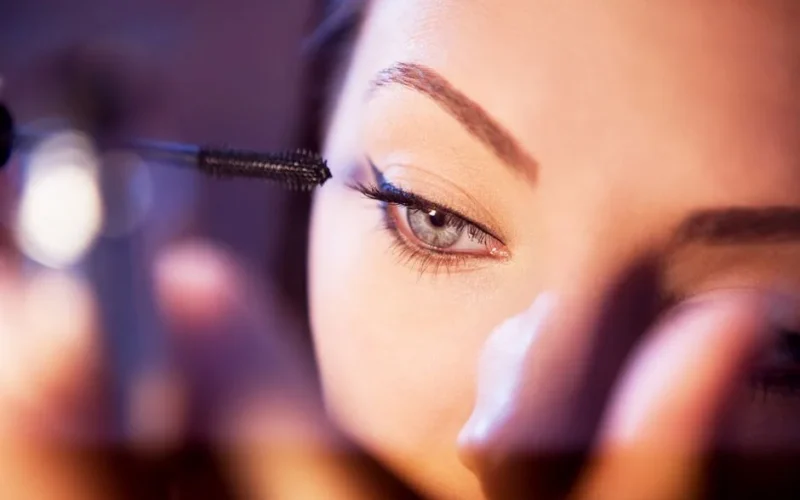 Detailed close-up of a woman applying mascara with focus on her eye.