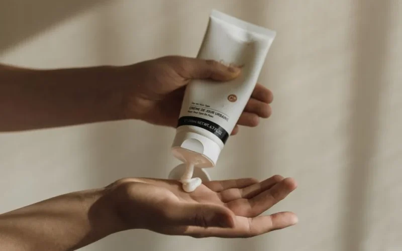 Close-up of a woman squeezing lotion onto her hand, emphasizing skincare and self-care routine.