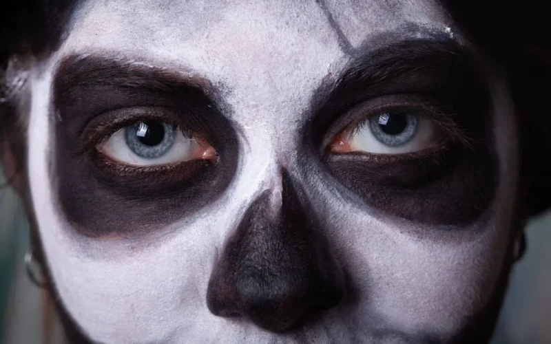 Intense close-up of a face painted with spooky Halloween skull makeup, featuring haunting eyes.