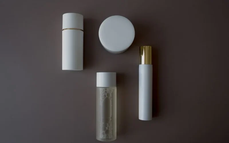 Top view of various skincare bottles and flasks on a sleek gray background.