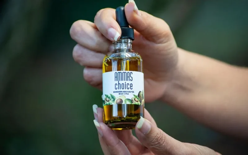 Close-up of hands holding a hair scalp oil bottle.