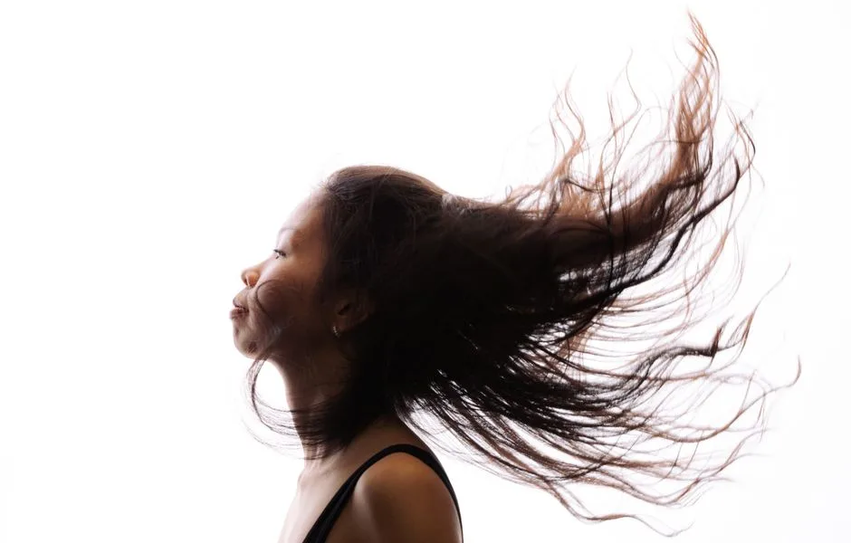 A high-contrast profile of a woman with her hair flowing, showcasing movement and expression.