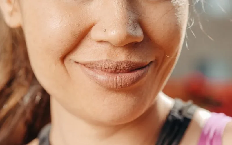 An extreme close-up of a smiling woman's lips and nose, capturing natural beauty and skin texture.