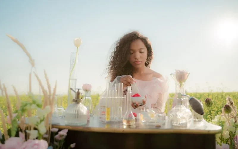 A young woman experimenting with perfumes at a table in a sunny meadow.