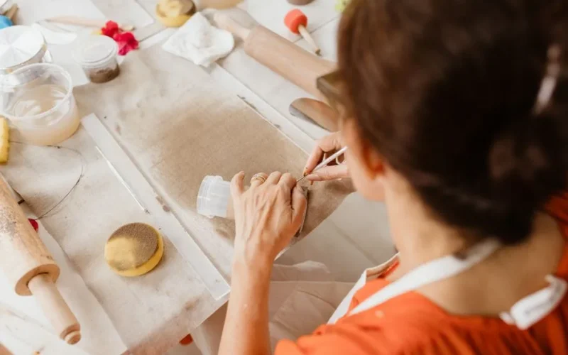 Adult woman crafting with fabric and tools indoors, showcasing creativity and skill.