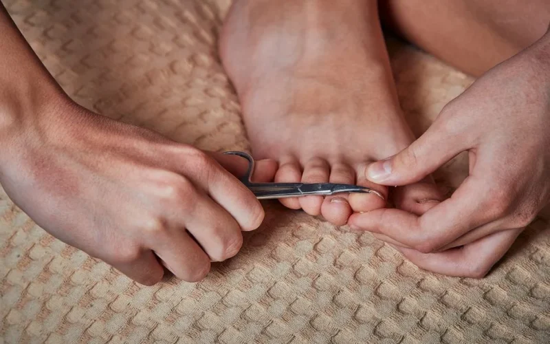 Detailed image of hands trimming toenails, showcasing personal foot care routine.