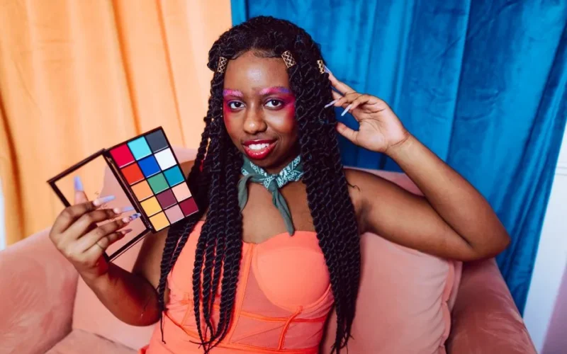 A stunning portrait of a woman with vibrant makeup and colorful eyebrows indoors.