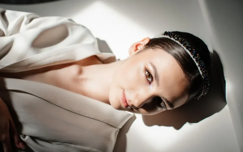 Glamorous portrait of a young woman with elegant attire and a headband, highlighting natural beauty.