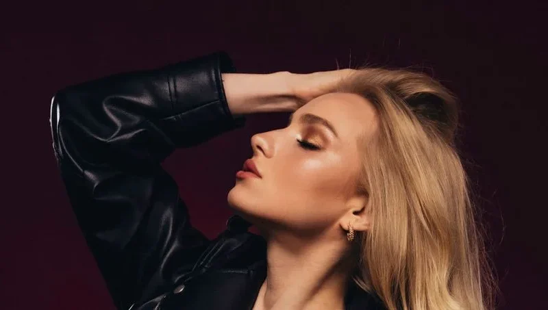 A beautiful young blonde woman poses gracefully with eyes closed, exuding elegance and style.