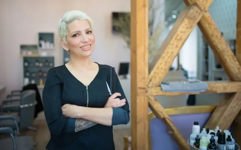 A confident female hair stylist smiling in a contemporary salon in Portugal.