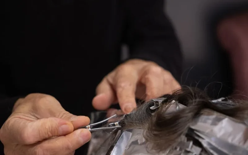 Detailed shot of a hairdresser applying hair color to a client's hair with foils.