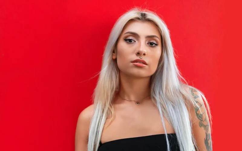 Portrait of a fashionable woman with platinum blonde hair and a bold red background, emphasizing modern style.