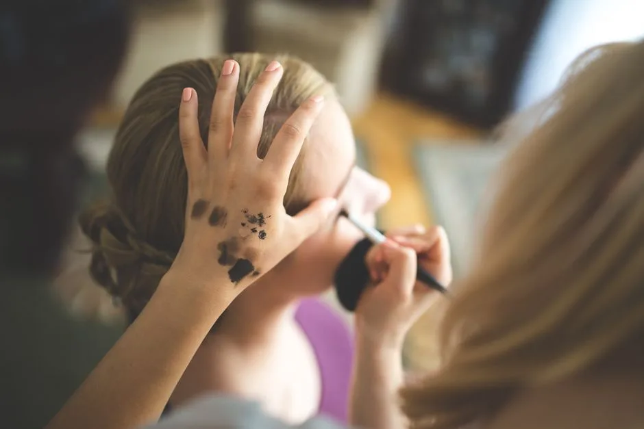 Close-up of a makeup artist applying cosmetics to a woman's face indoors.