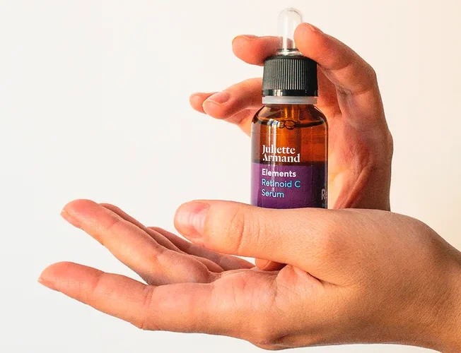 Close-up image of hands holding a cosmetics serum bottle, perfect for skincare themes.