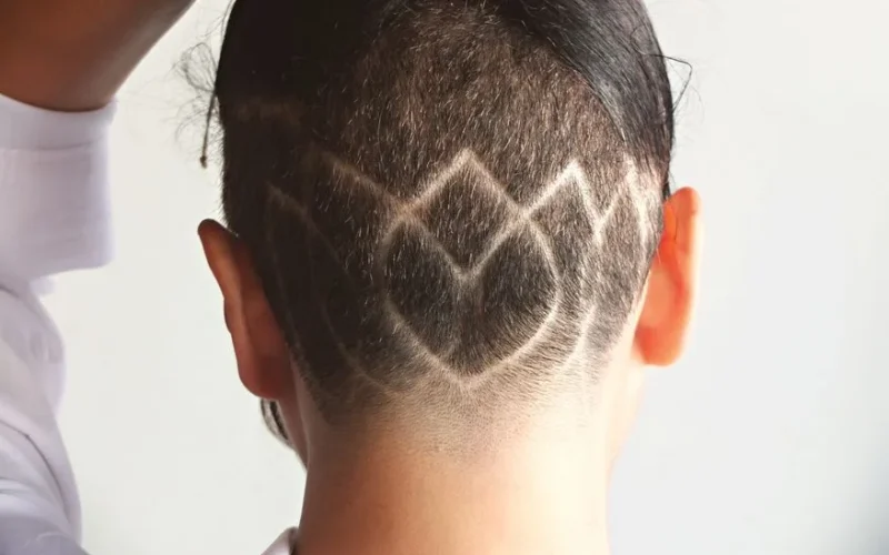 A unique undercut hairstyle featuring intricate geometric patterns shaved into the hair.