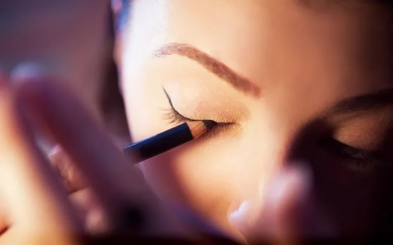 A woman applying eyeliner in a detailed close-up of an eye-focused beauty routine.