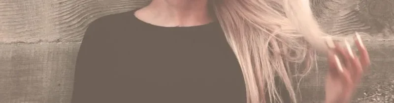 Close-up portrait of a woman with long, flowing blonde hair against a textured background.