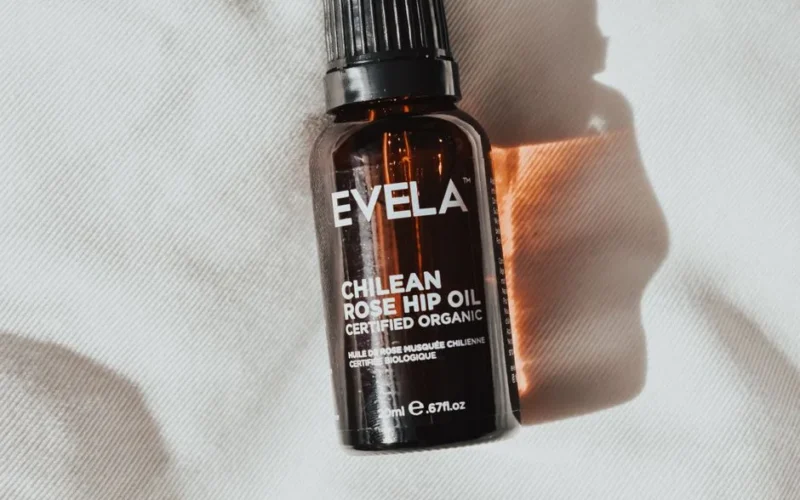 Close-up of amber bottle containing certified organic Chilean rose hip oil, with soft lighting and shadows.