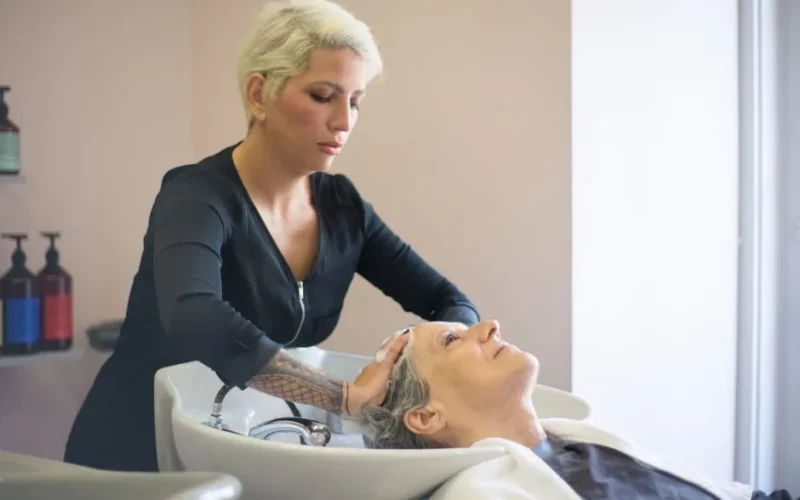 A hairdresser providing a relaxing hair wash to a senior woman in a salon setting.