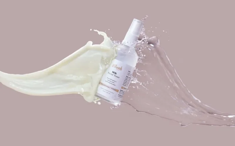 High-speed capture of milk and water splashing around a facial toner bottle, highlighting skincare product.