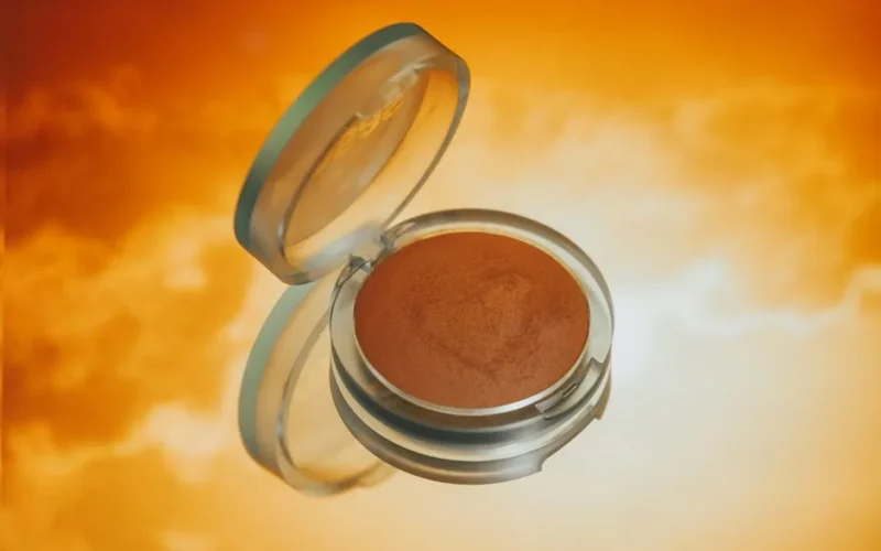Bronzer illuminating a vibrant orange backdrop, ideal for makeup visuals.