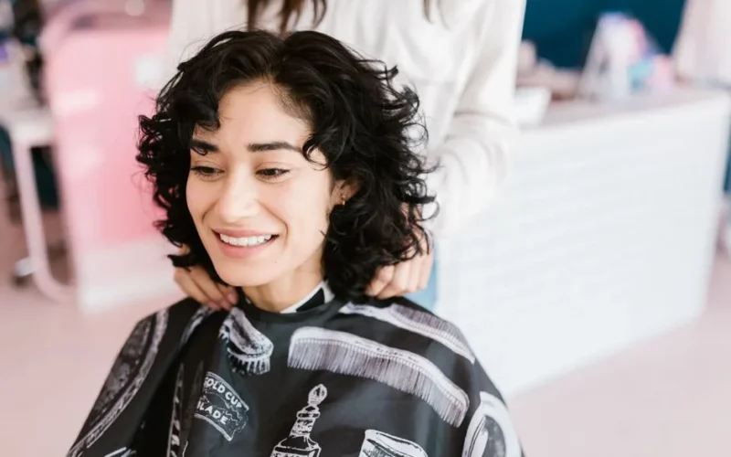A cheerful woman getting a haircut at a salon, showcasing a positive self-care experience.